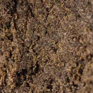 Macro shot of Maroccan Hash 60% THCX, dry sandy dark brown grain